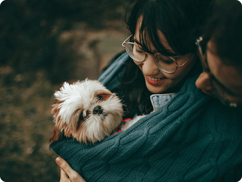A woman holding a small dog in her arms.